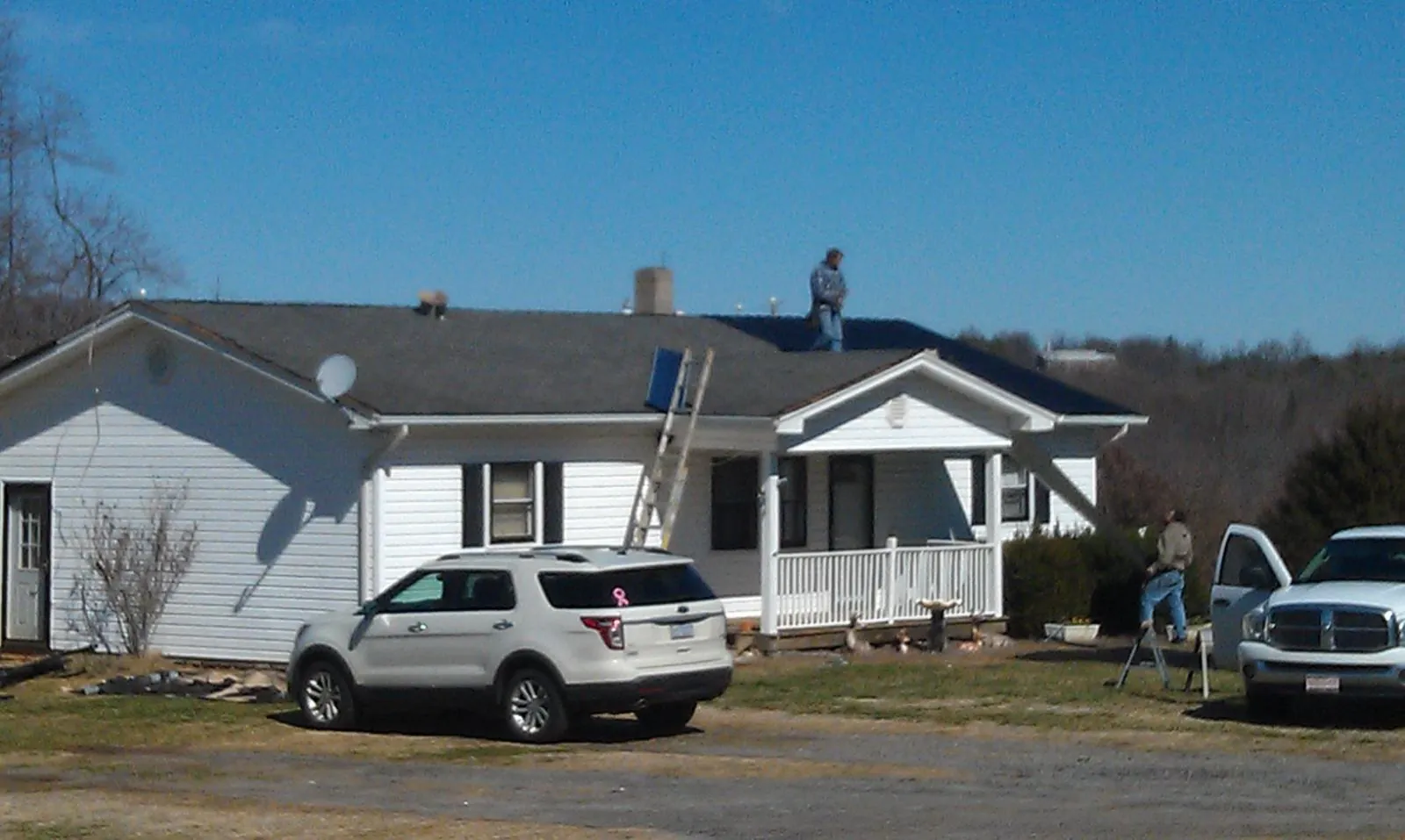Roofers stripping shingles from a white ranch house roof in Elkton